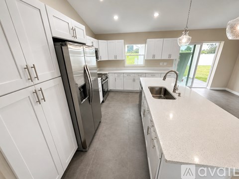 A modern kitchen with white cabinets and stainless steel appliances.