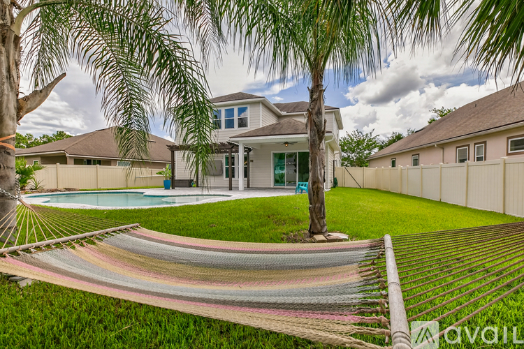 A hammock is strung between two trees in a backyard.