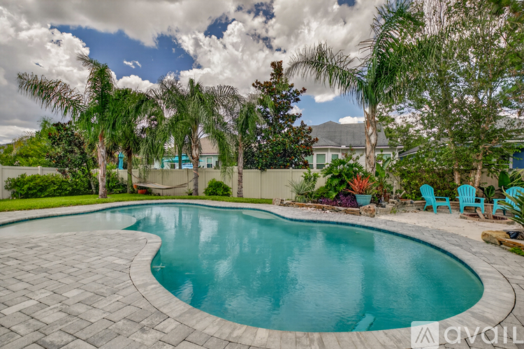 A swimming pool surrounded by trees and a cloudy sky.