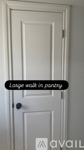 A white door with a black handle and a text that says "Large walk in pantry".