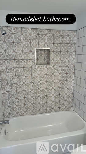 A remodeled bathroom with a white tub and patterned tile.
