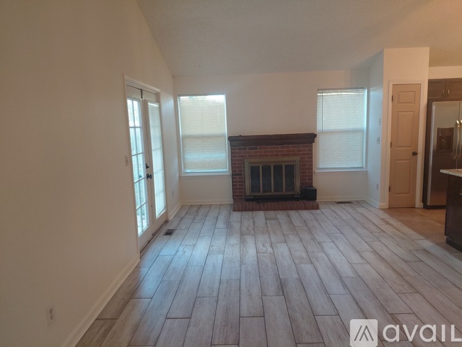 A room with wooden flooring and a brick fireplace.