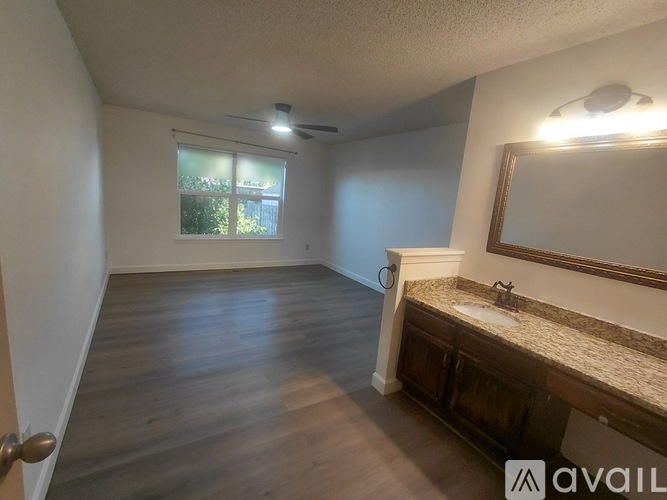 A bathroom with a sink, mirror, and wooden floors.