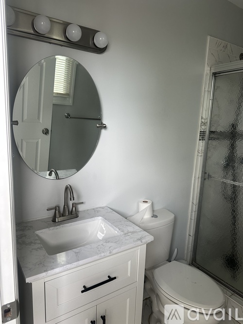 A bathroom with a sink, toilet, and mirror.