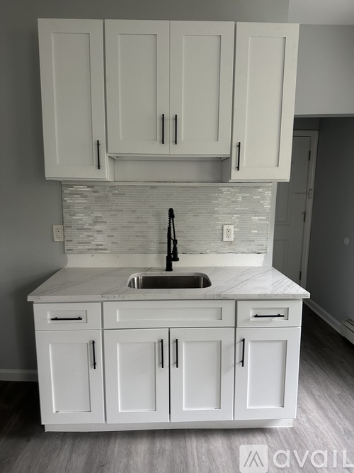 A kitchen with white cabinets and a marble countertop.