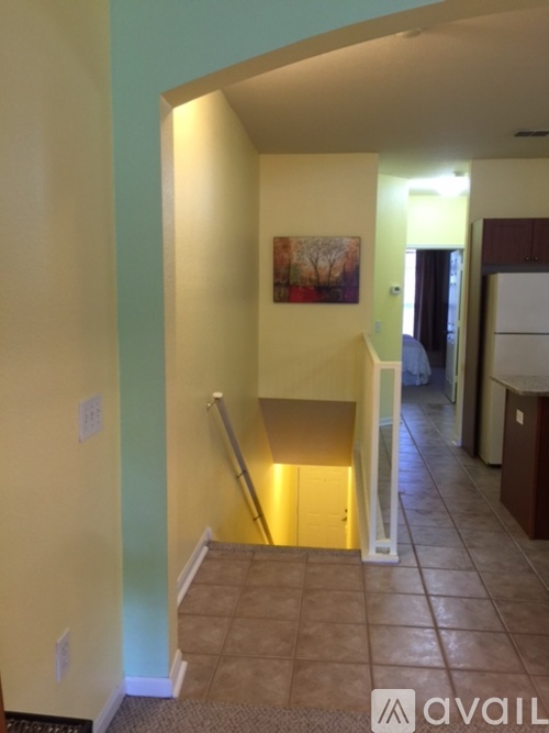 A hallway with a painting on the wall and a staircase.