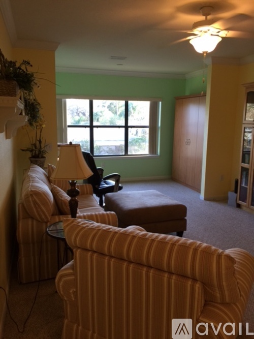 A living room with a striped chair and a lamp.