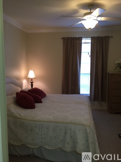 A bedroom with a bed, a lamp, and a window with curtains.