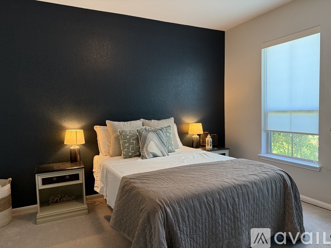 A bedroom with a bed, nightstand, and window.