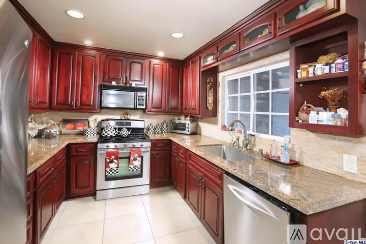 A kitchen with red cabinets and a stainless steel oven.