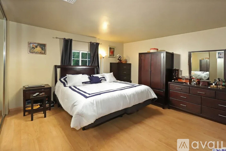 A bedroom with a bed, nightstand, and wardrobe.
