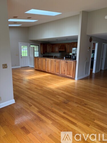 A room with wooden floors and a kitchen area with wooden cabinets.