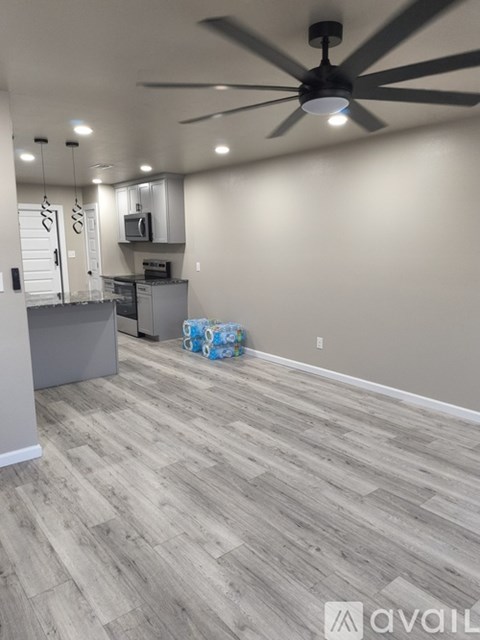 A room with a ceiling fan and wooden flooring.