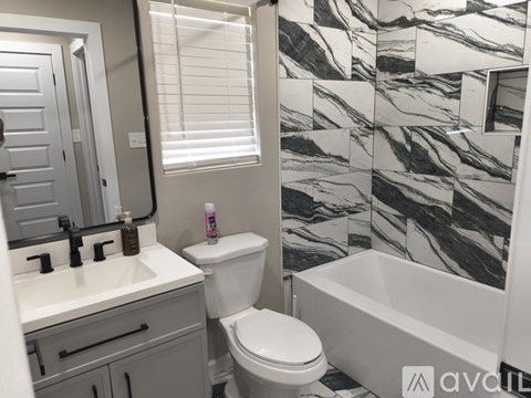 A bathroom with a marble wallpaper and a white toilet.