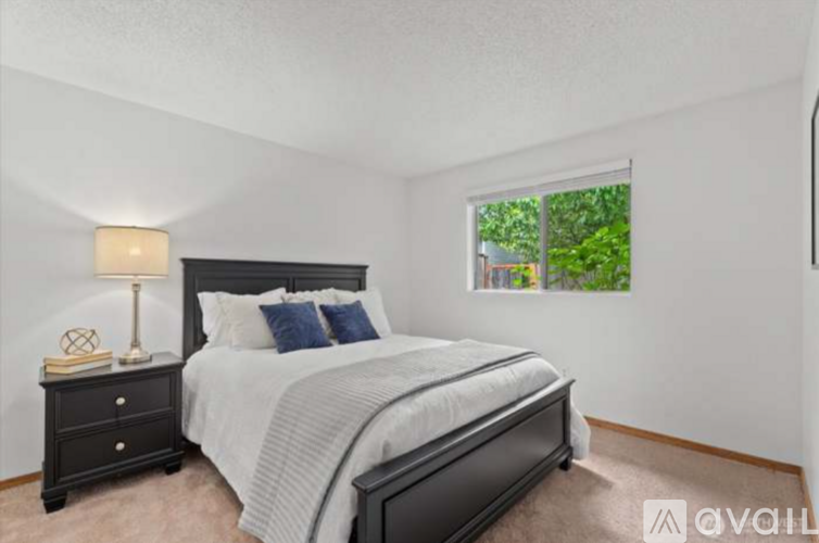 A bedroom with a large bed and a nightstand with a lamp.