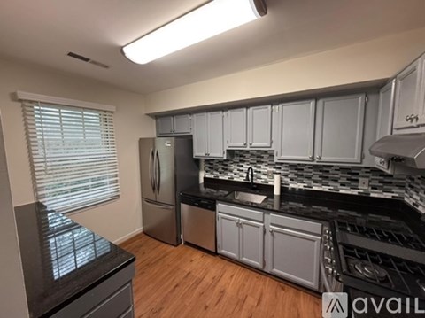 A kitchen with a black countertop and stainless steel appliances.