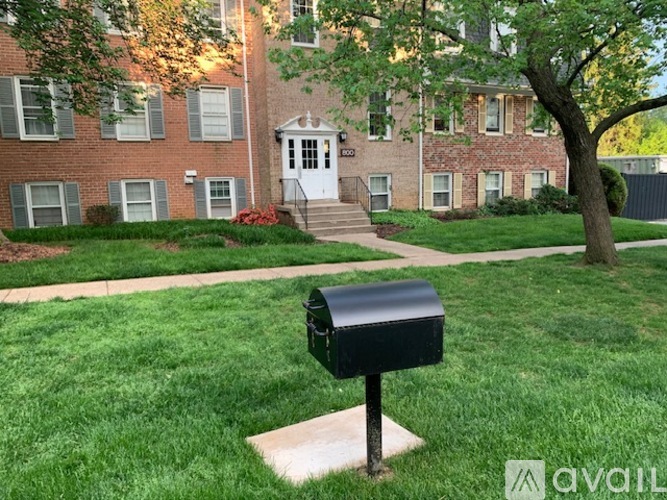 A black mailbox sits on a grassy area in front of a brick building.
