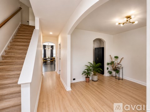 A hallway with a staircase on the left and a door on the right.