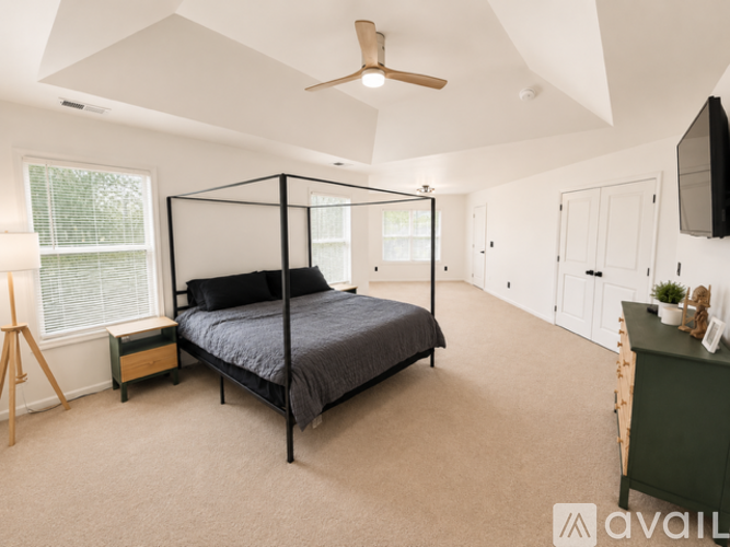 A bedroom with a four poster bed and a ceiling fan.