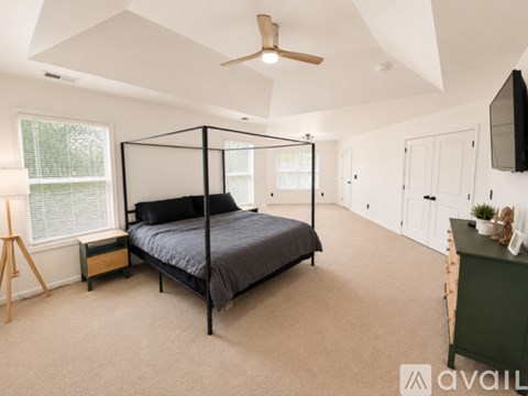 A bedroom with a four poster bed and a ceiling fan.