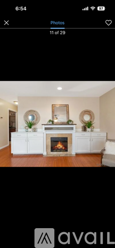A white fireplace with a mirror above it and a plant to the left.