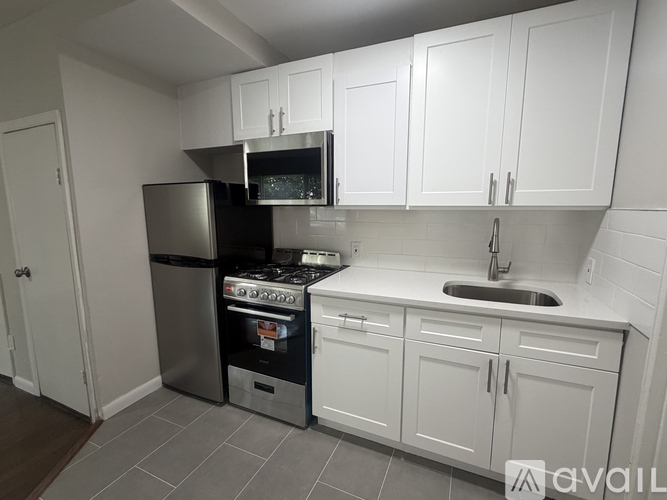A kitchen with white cabinets and a black refrigerator.