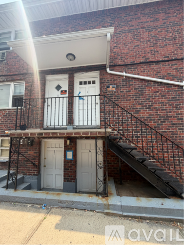 A red brick building with a white door and a staircase leading to the door.