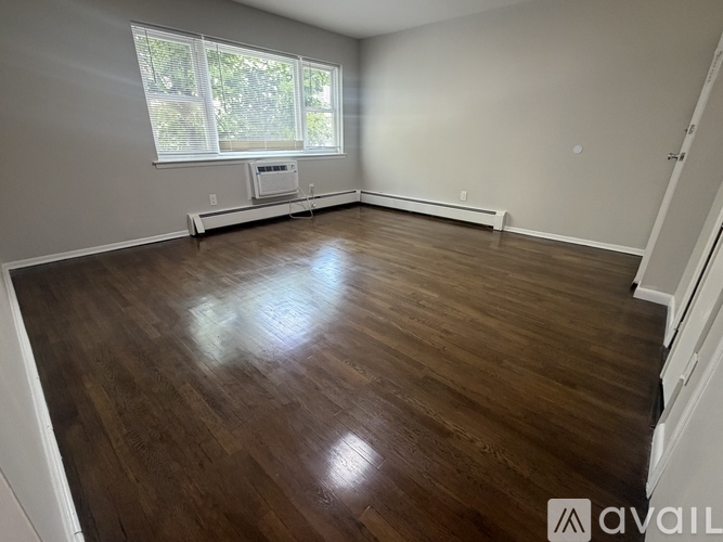 A room with wooden flooring and a window with blinds.
