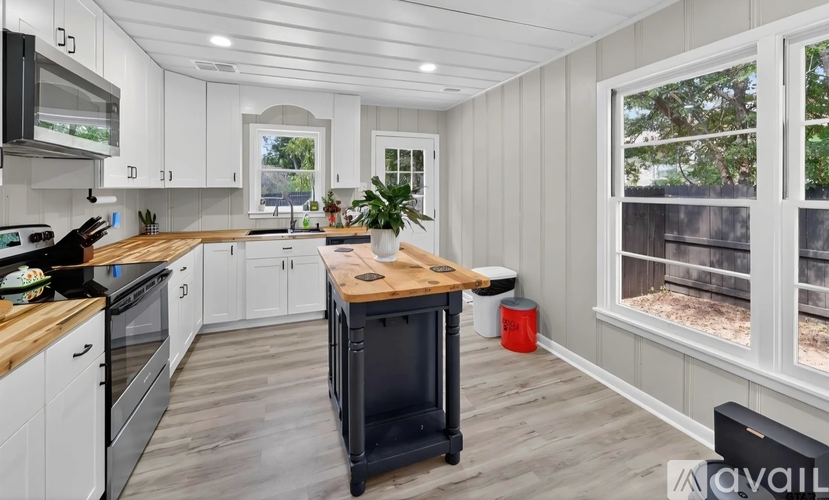A kitchen with white cabinets and a wooden island.