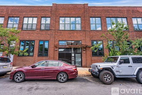 A red car is parked in front of a brick building.