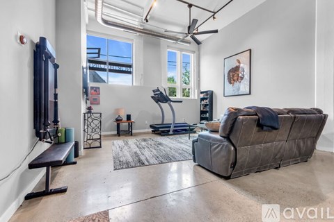 A living room with a grey couch and a black treadmill.