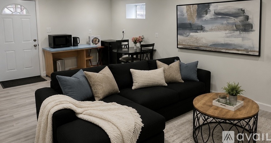 A living room with a black couch and a painting on the wall.