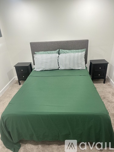 A bed with a green cover and striped pillows is in the image.