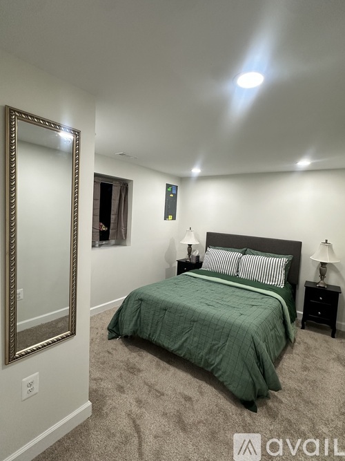 A bedroom with a bed, nightstand, and a mirror.