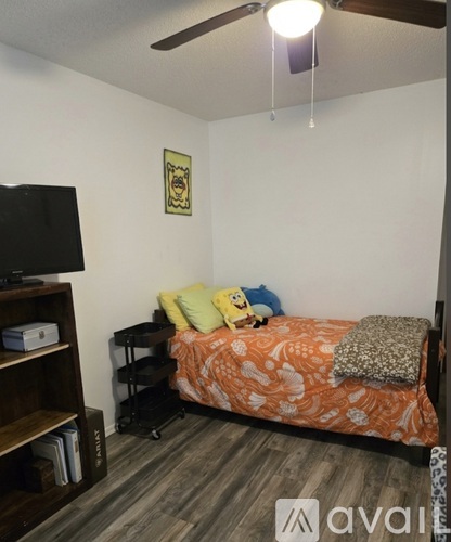 A bedroom with a bed, a television, and a ceiling fan.