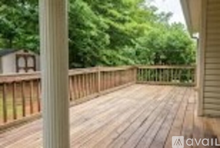 A wooden deck with a railing and trees in the background.