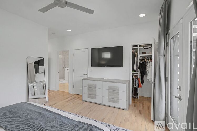A spacious room with a television, a fan, and a wardrobe.