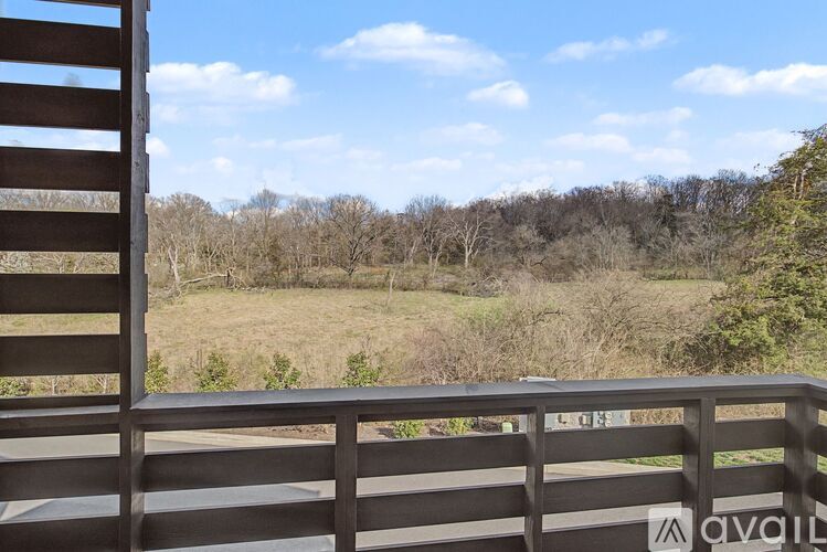 A wooden balcony with a view of a field and trees.