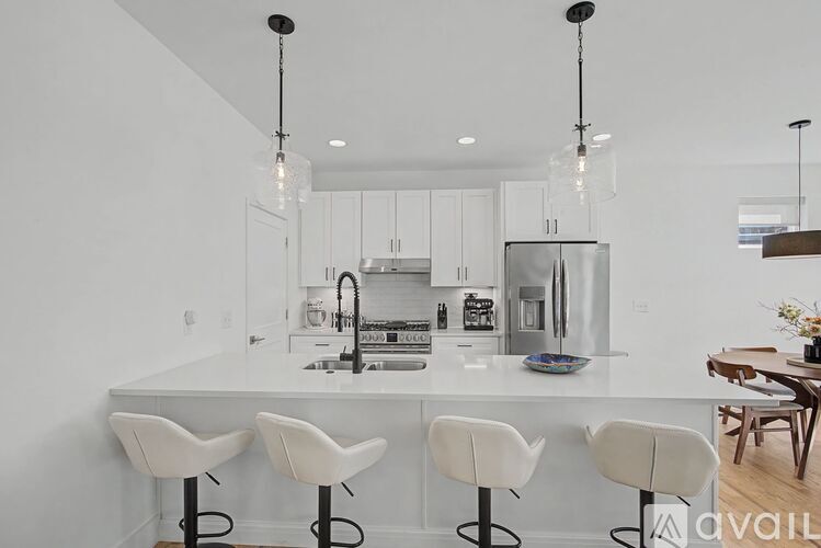 A modern kitchen with white chairs and a white island.