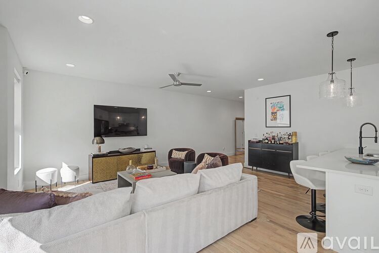 A living room with a white couch and a television on the wall.