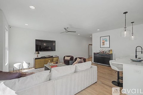 A living room with a white couch and a television on the wall.