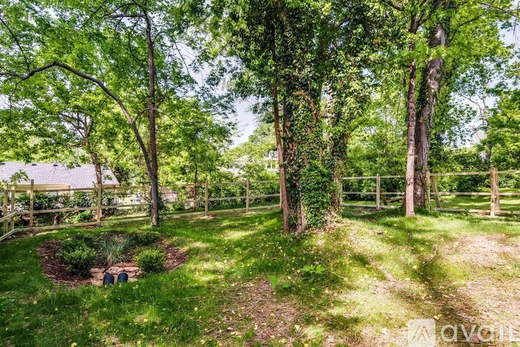 A lush green garden with a fence and trees.