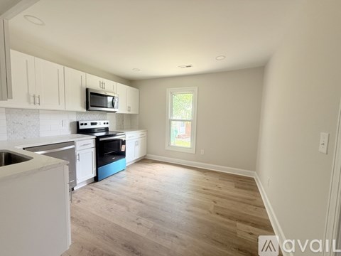 A kitchen with white cabinets and a wooden floor.