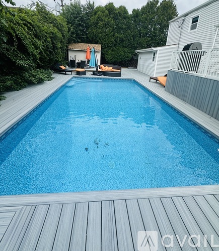 A pool with a wooden deck and a house in the background.