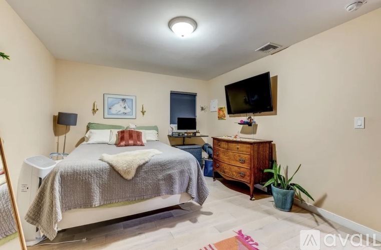 A bedroom with a bed, dresser, and a television.