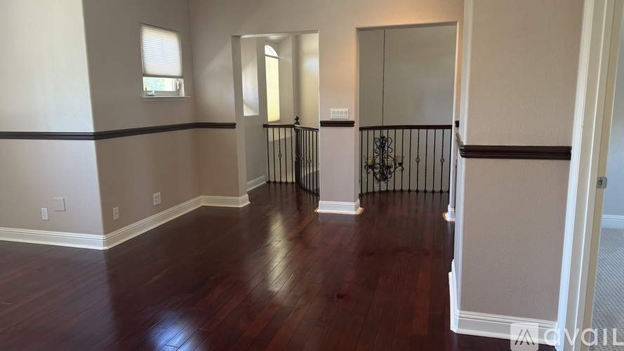 A room with wooden floors and a balcony with a railing.
