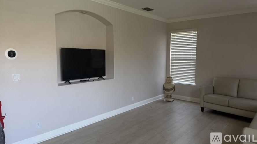 A living room with a flat screen TV mounted on the wall and a couch.