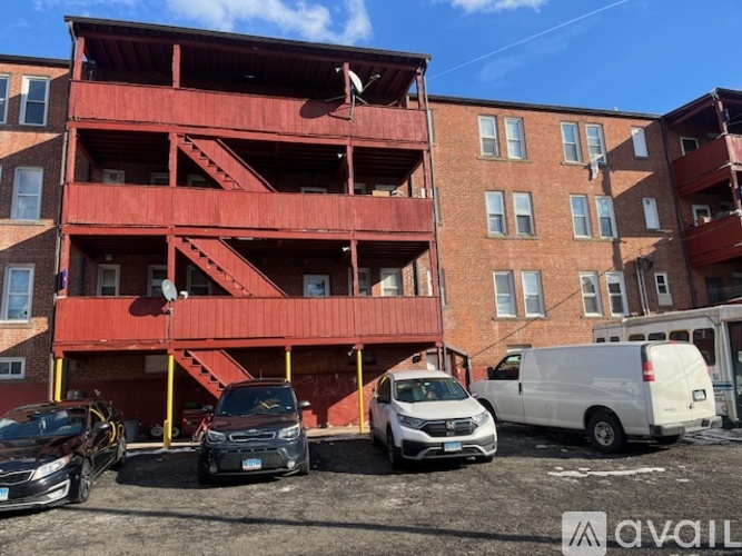 A red apartment building with cars parked in front.