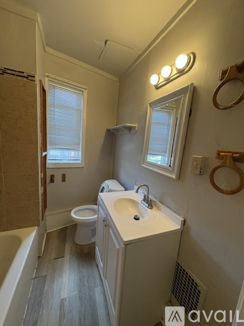 A bathroom with a toilet, sink, and mirror.