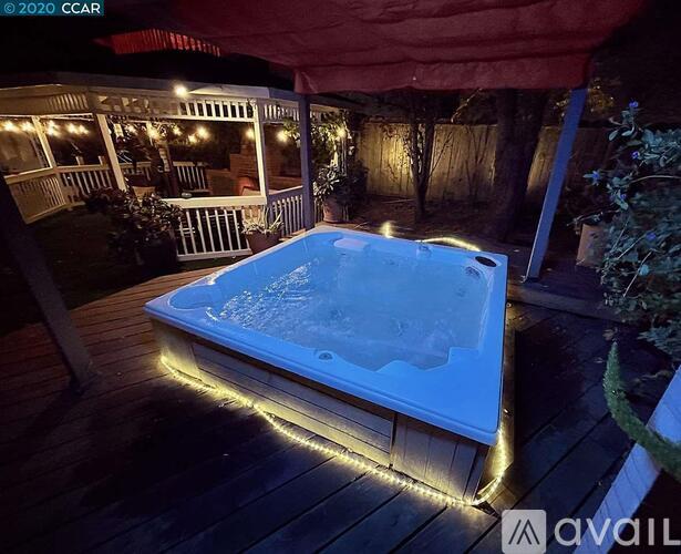 A hot tub is lit up at night on a deck.
